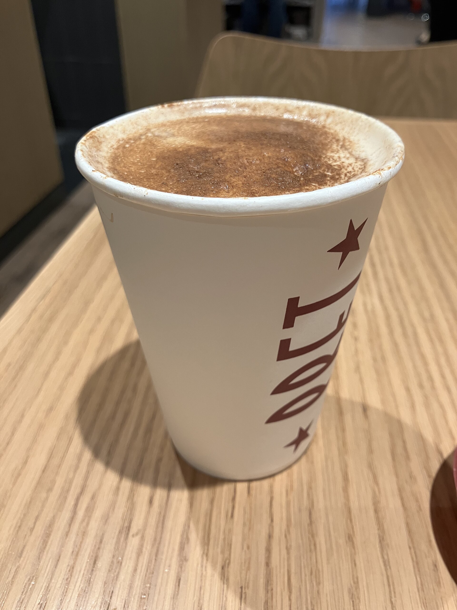 Gorący pumpkin spice latte w papierowym kubku z przyprawą cynamonową